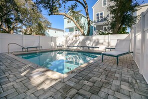 A swimming pool with a brick deck, surrounded by white fences and trees. - Coastal Daze: Pool & Short Walk to Beach (Surfside Beach)