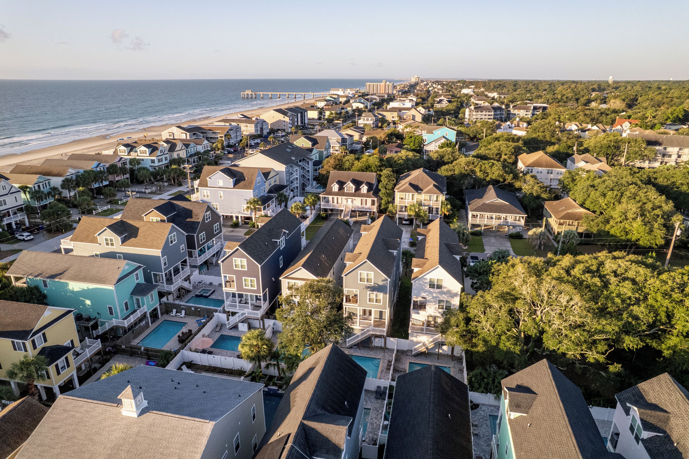 A coastal residential area with houses, a beach, and a pier.