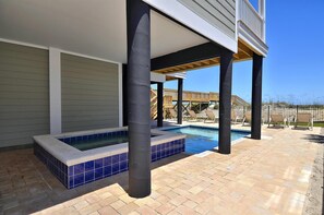 Ein Poolbereich mit Whirlpool, überdachter Terrasse und Holzterrasse mit Liegestühlen.
