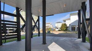 An outdoor covered area with concrete flooring, metal beams, and a view of residential buildings in the background. - Gone Coastal: Short Walk to Beach & Shared Pool (Murrells Inlet)