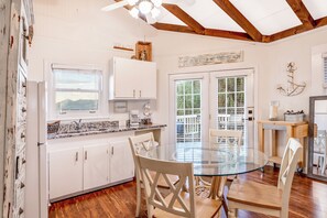 A kitchen with white cabinets, a glass-top dining table, and a wooden ceiling. - Good Ol' Days: Private Pool, Hot Tub & Steps to the Beach (Murrells Inlet)