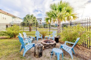A backyard with a fire pit, blue chairs, and a palm tree. - Good Ol' Days: Private Pool, Hot Tub & Steps to the Beach (Murrells Inlet)