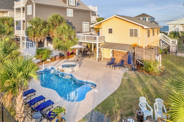 Zona residencial con piscina, mobiliario exterior y patio cercado.