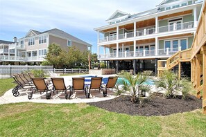 Un bâtiment à deux étages doté d’un patio couvert, d’un espace extérieur aménagé avec des sièges et d’une piscine.