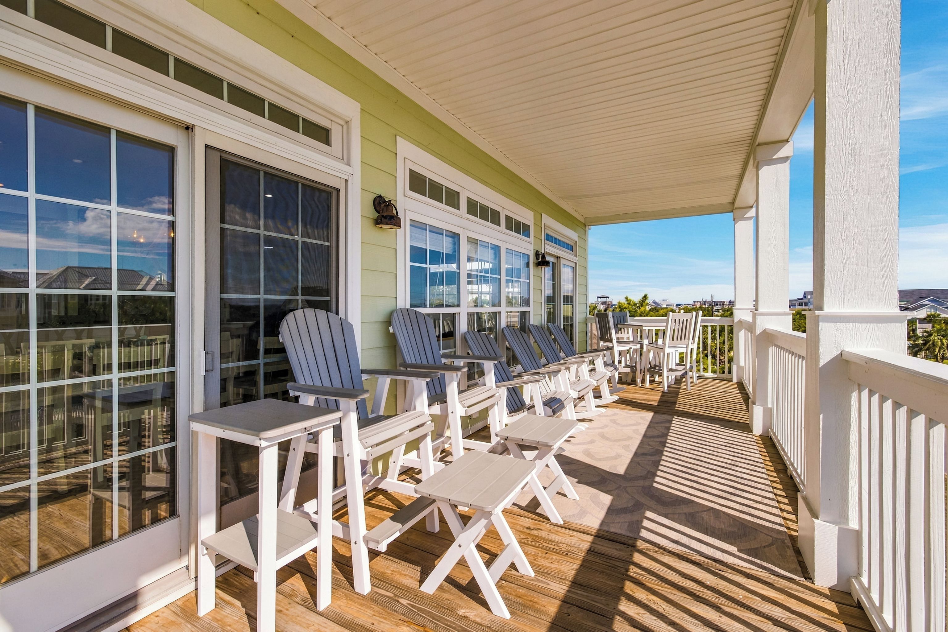 A covered outdoor seating area with tables and chairs, large windows, and a view of the surrounding landscape.
