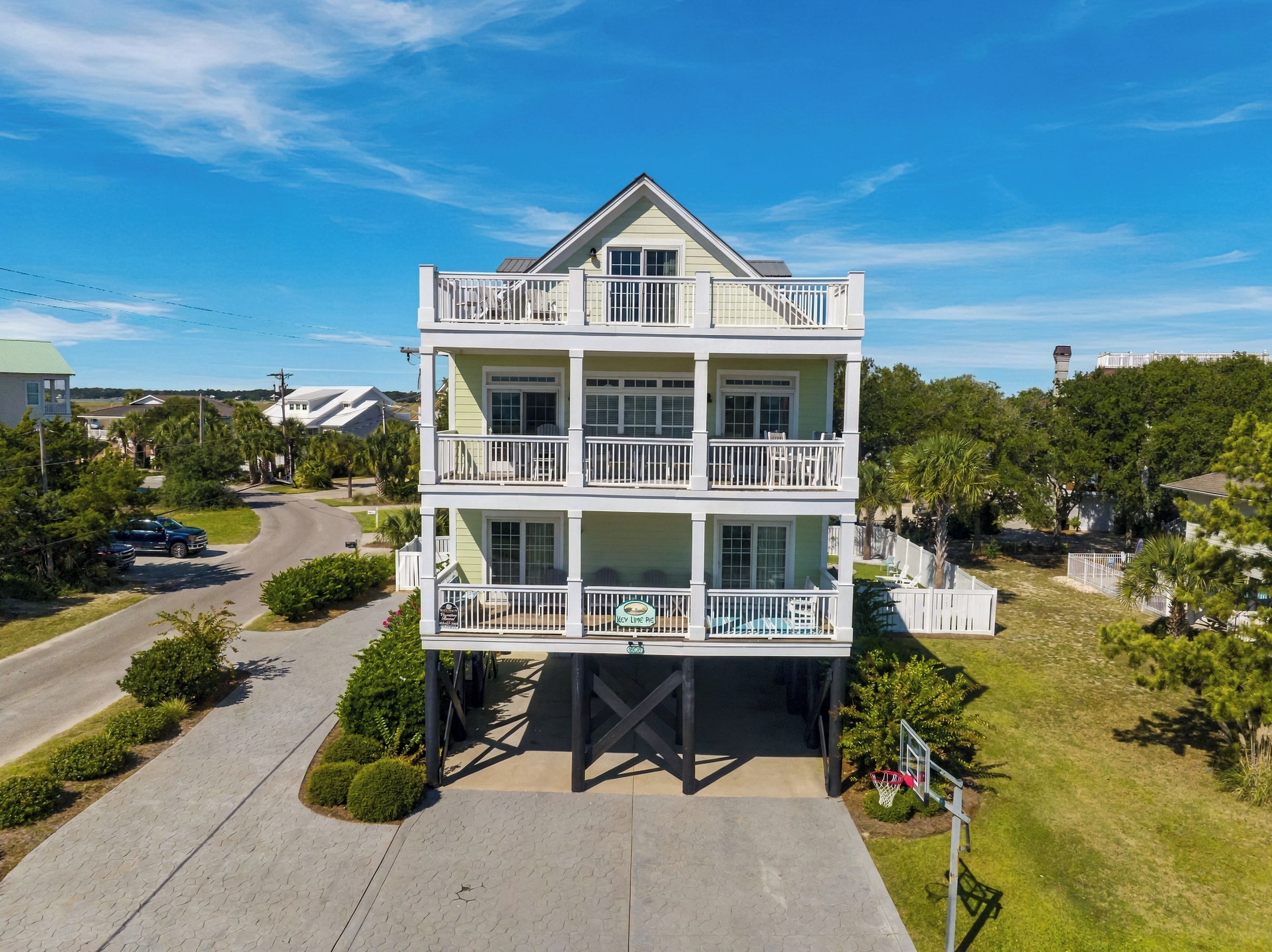 A multi-story building with balconies, a paved driveway, and a basketball court.