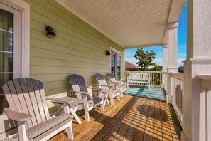 Eine überdachte Veranda mit Adirondack-Stühlen und einem kleinen Poolbereich.