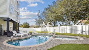 A swimming pool with a brick border, surrounded by a grassy area and a white fence. - Key Lime Pie: Ocean Views, Pool, Steps to Beach (Murrells Inlet)