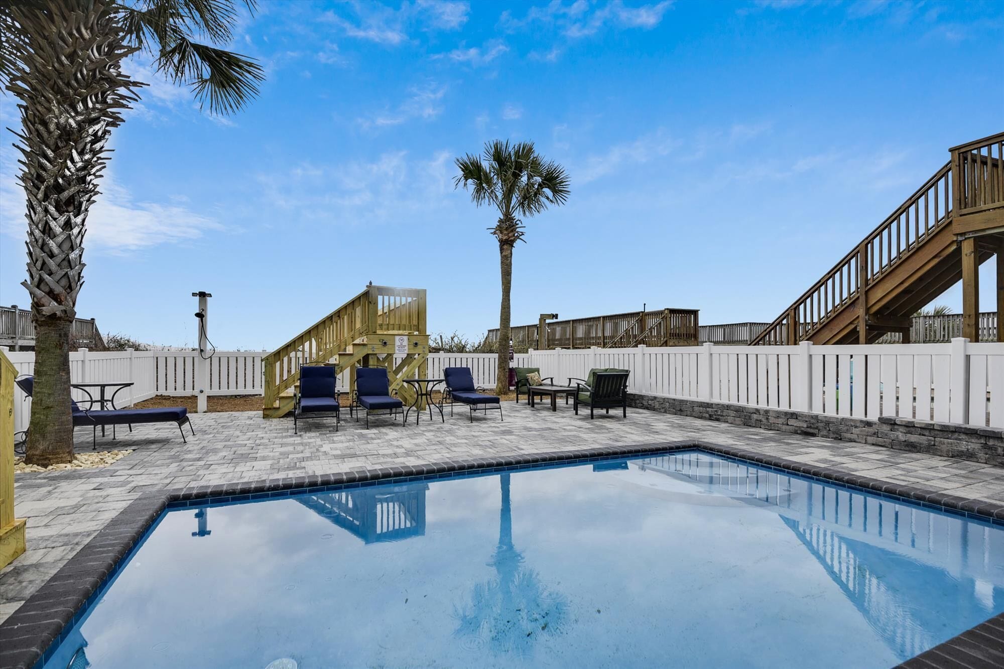 A swimming pool with lounge chairs and a wooden deck.