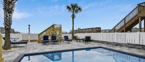 A swimming pool with lounge chairs and a wooden deck.