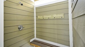 Ein Raumeck mit Holzwandverkleidung und einem Metallhandtuchhalter mit der Aufschrift 'Handtücher - Badeanzüge - Verspieltheit'.