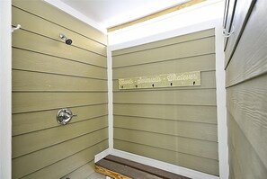 Ein Raumeck mit Holzwandverkleidung und einem Metallhandtuchhalter mit der Aufschrift 'Handtücher - Badeanzüge - Verspieltheit'.