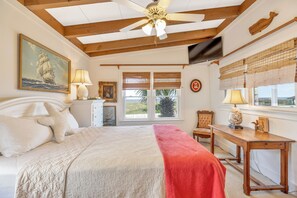 A bedroom with a bed, a desk, a chair, a ceiling fan, and a window with blinds. - Panacea: Oceanfront Charm with Pool, & Private Beach Walkway (Murrells Inlet)
