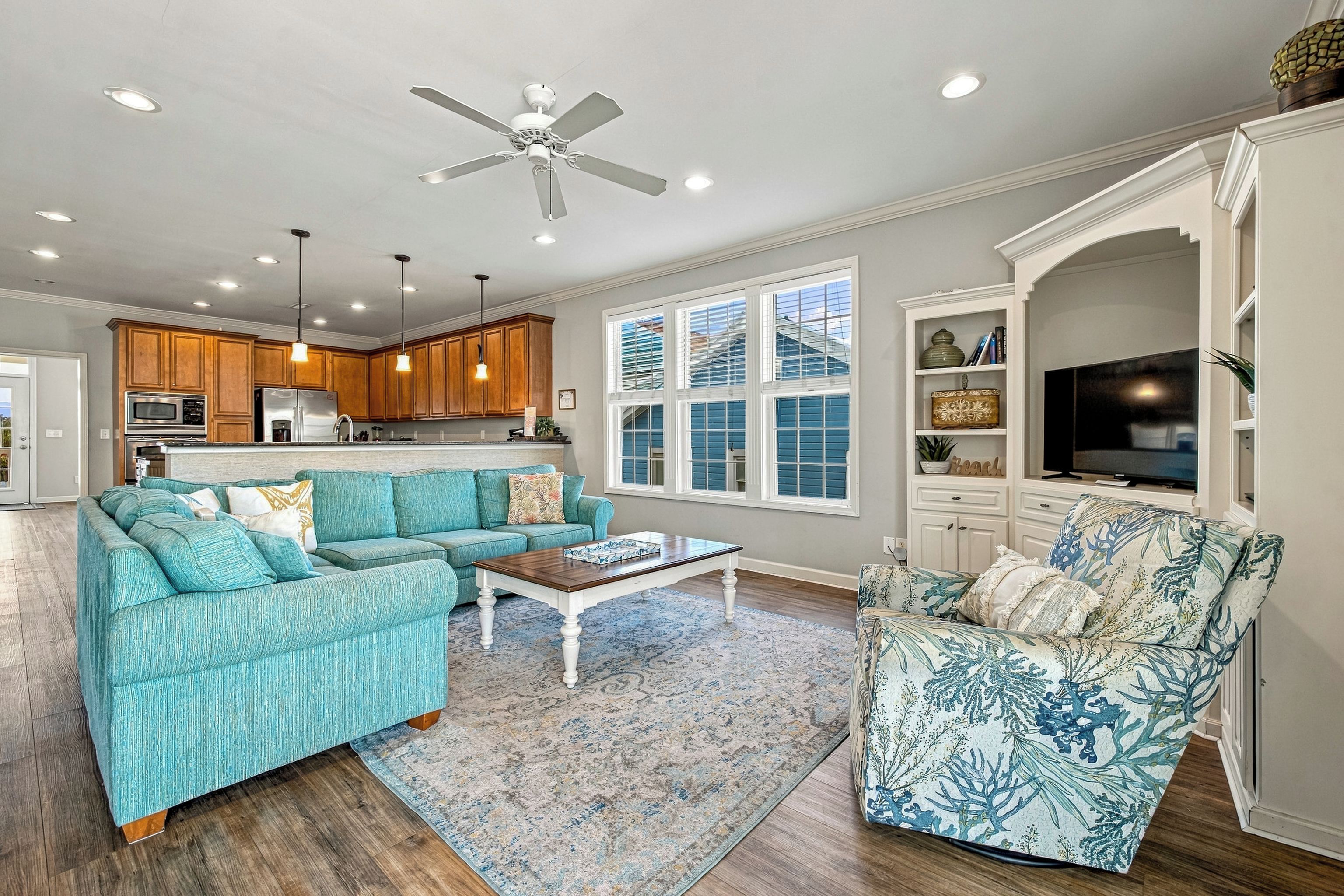 A spacious living room with a teal sofa, a patterned armchair, and a coffee table.