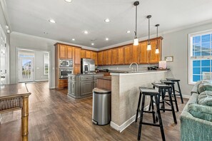 A spacious kitchen with wooden cabinets, stainless steel appliances, and a central island. - Peachy Keen: Private Pool, Ocean Views & Steps from the Sand (Murrells Inlet)