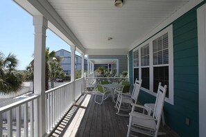 Eine überdachte Veranda mit weißen Geländern, einem Tisch und Stühlen.