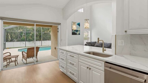 Una cucina moderna con una grande isola, mobili bianchi e vista su una piscina.