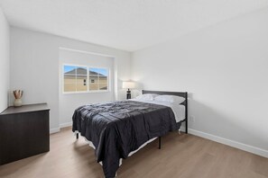A bedroom with a bed, a bedside table, a lamp, and a window with a view of a building. - 5BR Private Pool Retreat  Near Disney (Kissimmee)