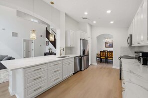 A modern kitchen with white cabinetry, stainless steel appliances, and a marble countertop. - 5BR Private Pool Retreat  Near Disney (Kissimmee)