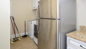Een keuken met een roestvrijstalen koelkast, een wasmachine en een dweil.