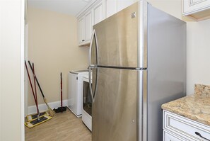 Eine Küche mit einem Edelstahl-Kühlschrank, einer Waschmaschine und einem Wischmopp.