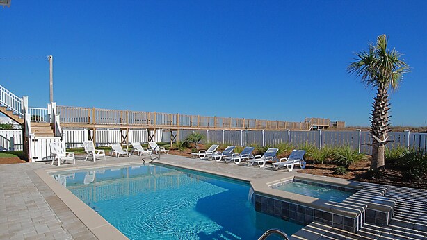 Una piscina con sillas de descanso y una terraza de madera.
