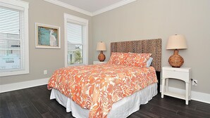 Un dormitorio con cama, dos mesitas de noche, cabecera y dos lámparas.