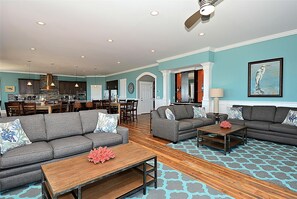 A spacious living room with two sofas, a coffee table, and a dining area with a kitchen in the background.