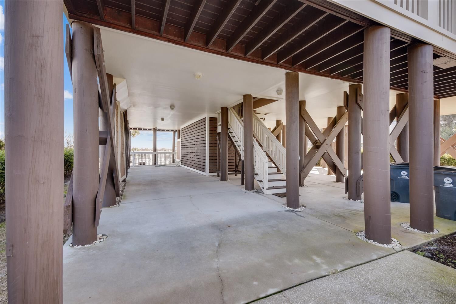 A covered walkway with wooden columns and a staircase leading to an upper level.