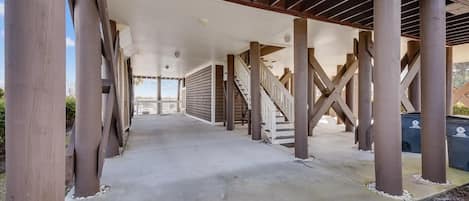 A covered walkway with wooden columns and a staircase leading to an upper level.