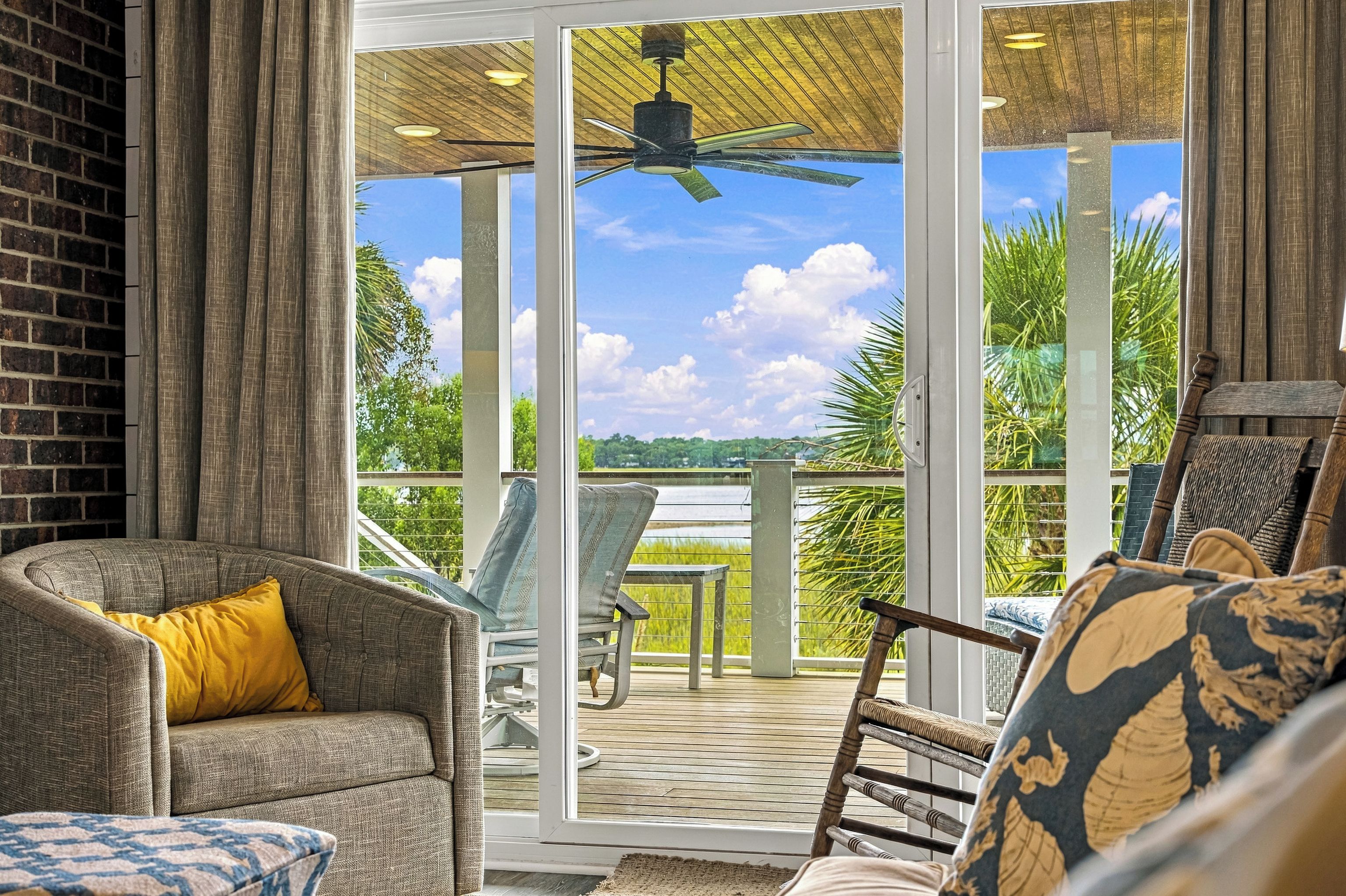 A spacious balcony with a view of a lush landscape, furnished with a sofa, chairs, and a table.