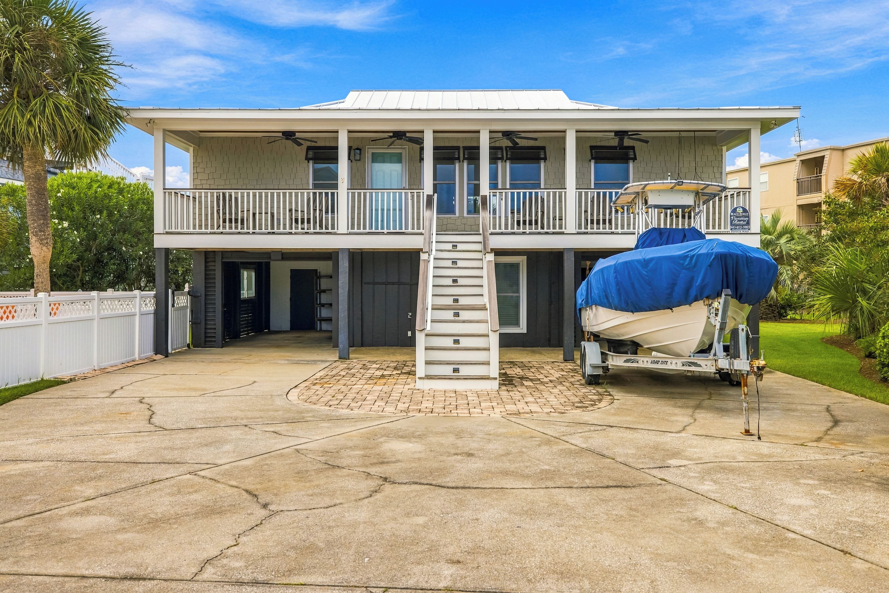 A two-story house with a covered front porch and a boat on a trailer.