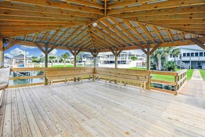 An open wooden deck with a bench, surrounded by a metal roof structure. - Triple Play: Inlet Front, Dock, Pool & Steps to the Beach (Murrells Inlet)