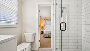 Een badkamer met toilet, douchecabine met glazen wanden en een betegelde wand.