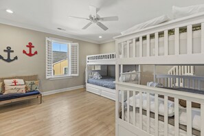 A child's bedroom with bunk beds, a ceiling fan, a window with shutters, and nautical-themed decor. - William's Wharf: Inlet Front, Dock, Pool & Steps to the Beach (Murrells Inlet)