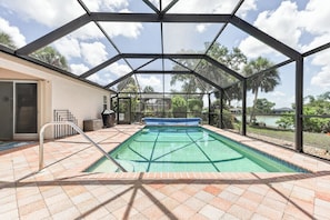 A covered swimming pool with a view of a lake and palm trees. - Rotonda West Getaway | Private Heated Pool Retreat (Rotonda West)