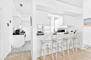 A modern kitchen with white cabinetry, a dining area with white chairs, and a tiled floor. - Rotonda West Getaway | Private Heated Pool Retreat (Rotonda West)