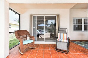 Ein überdachter Patio-Bereich mit einem Korbstuhl und einem Klappsessel.