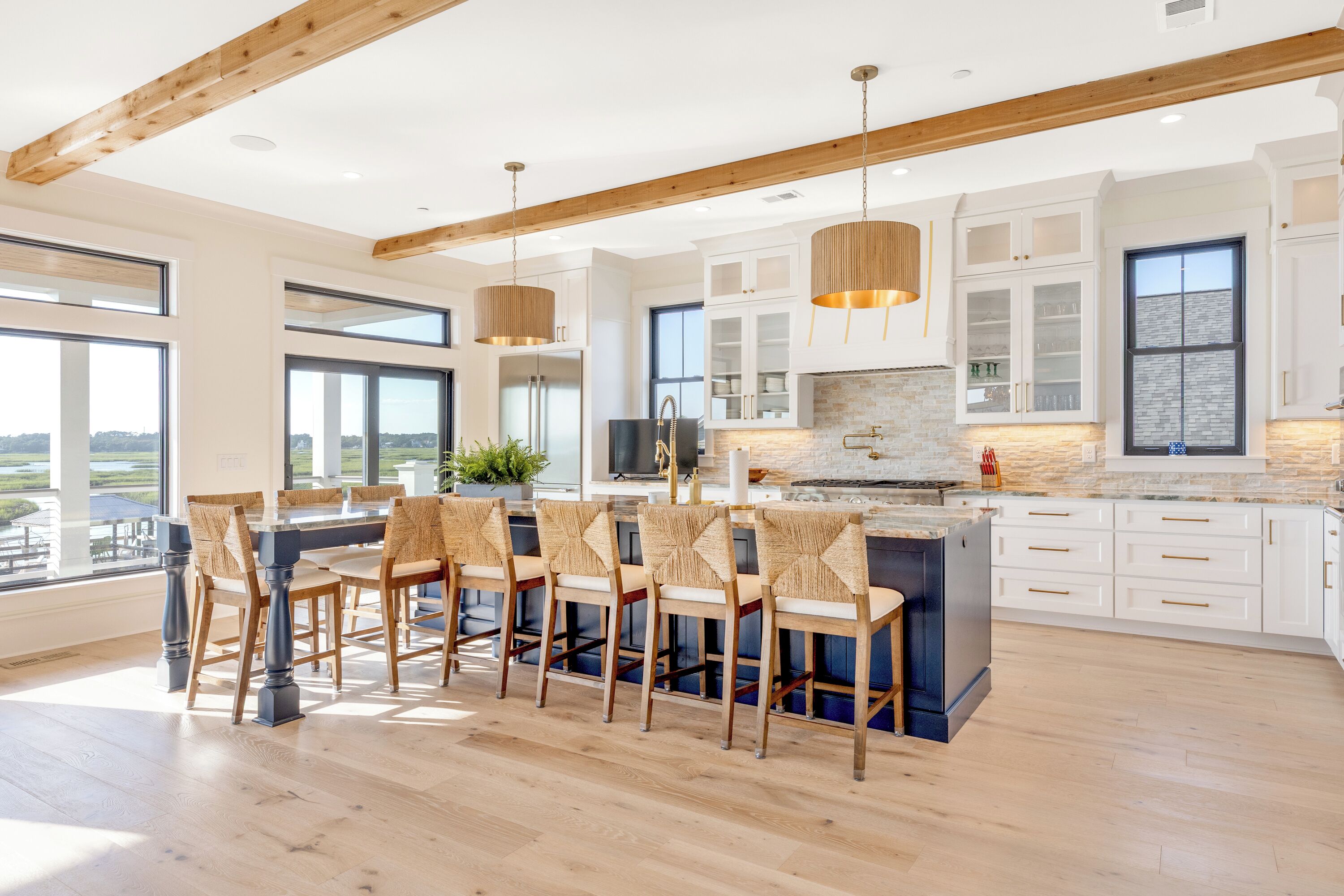 Una cucina moderna con una grande isola, travi in legno a soffitto e ampie finestre.