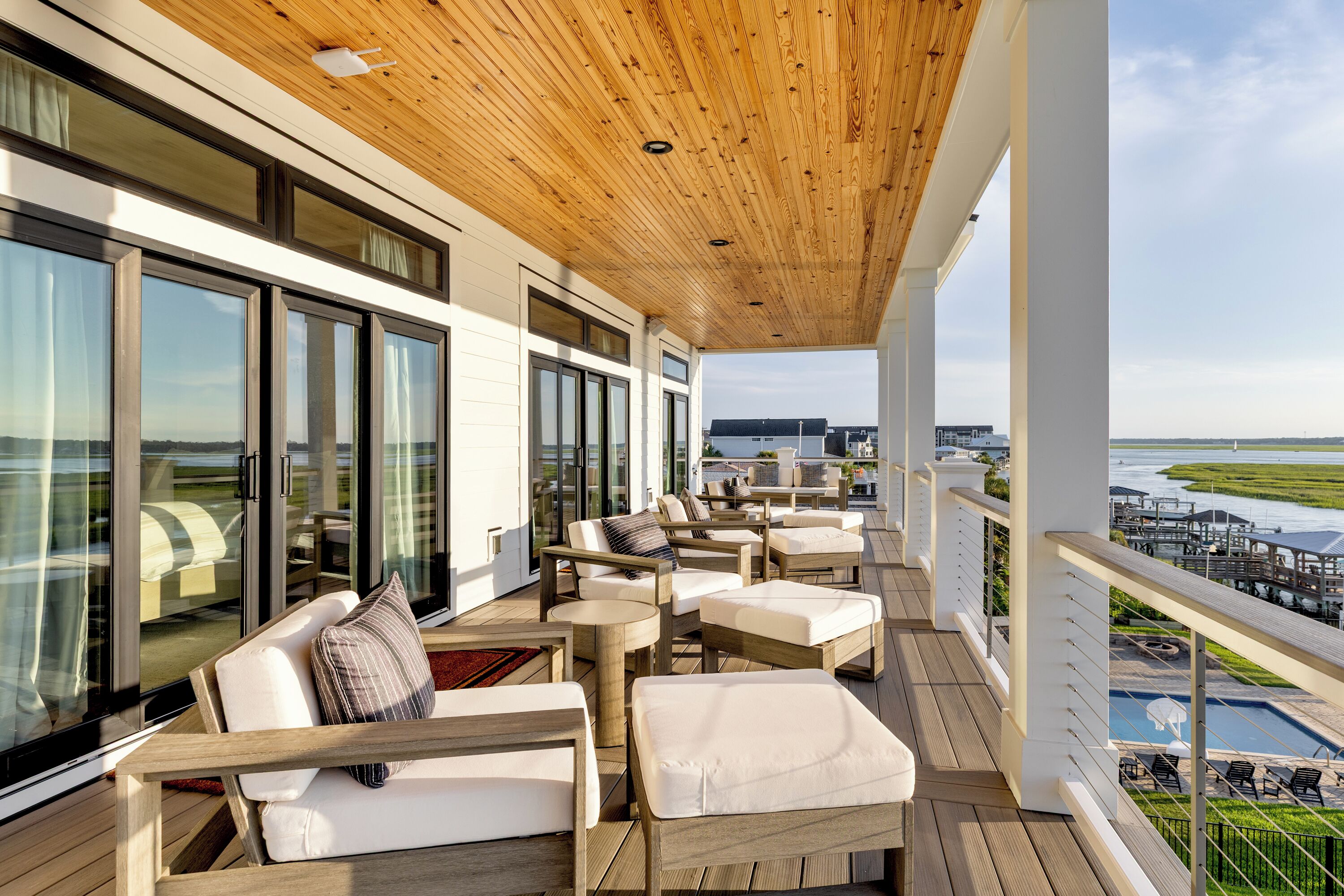 Ein Balkon mit Sitzgelegenheit im Freien, großen Fenstern und Blick auf ein Gewässer.