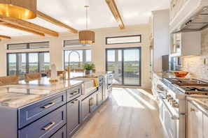 A modern kitchen with a large island, wooden beams, and a view of the outdoors. - Best Of Both Worlds: Views, Pool, Location & Luxury (Murrells Inlet)