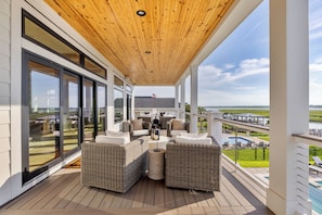 A covered outdoor area with wicker furniture, large windows, and a view of a pool and landscape. - Best Of Both Worlds: Views, Pool, Location & Luxury (Murrells Inlet)