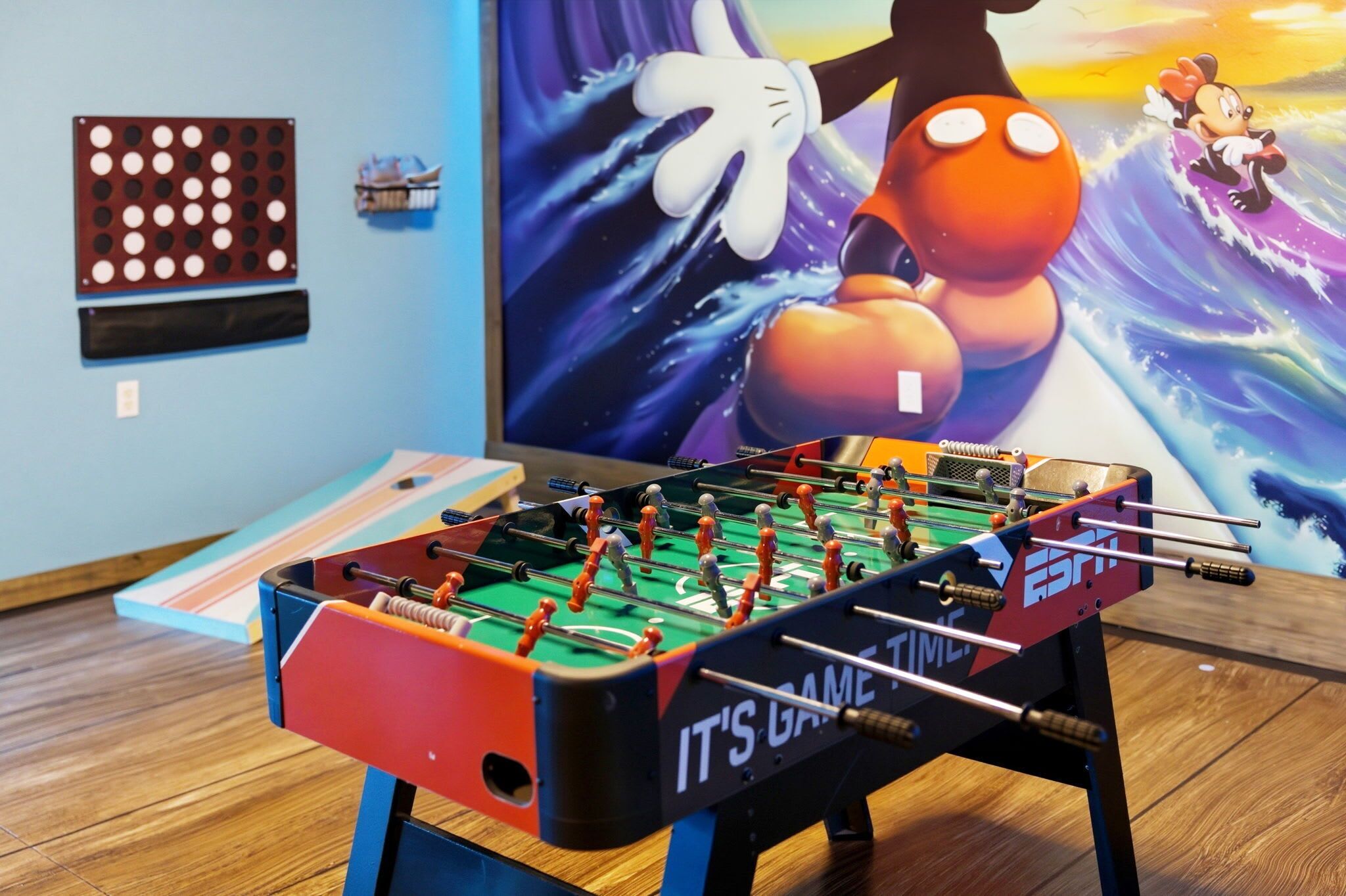 A foosball table in a room with a blue wall and a large poster.
