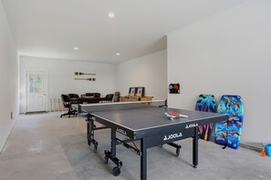 A ping pong table with a net, a desk, chairs, and a door with a map. - Upscale New Construction 4BR/3BA Coastal Retreat • 3-Min Walk to Beach •Sleeps 9 (Carolina Beach)