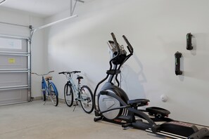 A garage with two bicycles and an exercise bike. - Upscale New Construction 4BR/3BA Coastal Retreat • 3-Min Walk to Beach •Sleeps 9 (Carolina Beach)