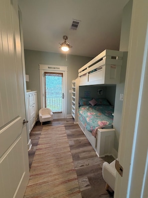 Um quarto com beliches, uma escrivaninha e uma cadeira.