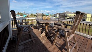 A wooden deck with a table and chairs, overlooking a residential area with houses and a clear sky. - House, 2 Masters, Hot Tub, Tiki & Game, Sleeps 12 (Bolivar Peninsula)