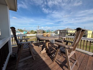 Eine Holzterrasse mit Tisch und Stühlen mit Blick auf ein Wohngebiet, Häuser und einen klaren Himmel.