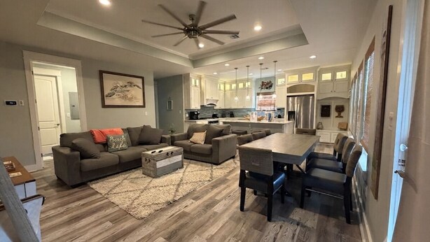 A spacious living room with a large sofa, a dining table, and a kitchen in the background. - House, 2 Masters, Hot Tub, Tiki & Game, Sleeps 12 (Bolivar Peninsula)