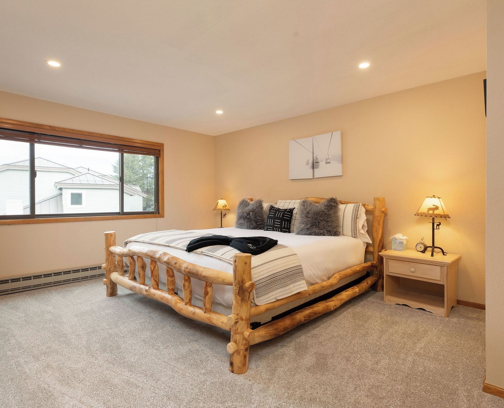 Un dormitorio con estructura de cama de madera, un ventanal grande y dos lámparas de noche.
